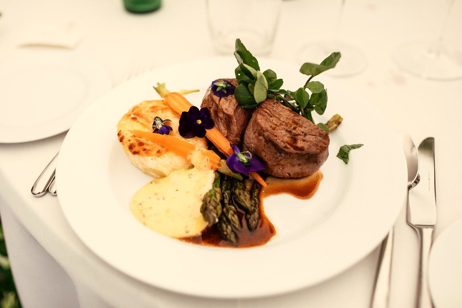 A beautifully plated beef fillet with dauphinoise, asparagus and edible flowers.