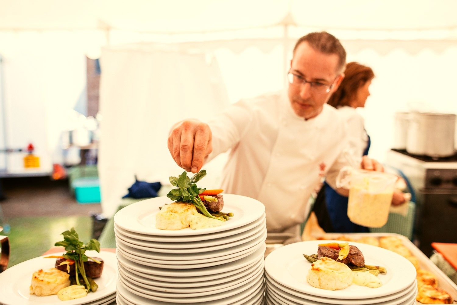 A chef adding the final garnish to a plated fillet dish.