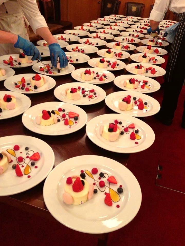 Rows of desserts finished with fresh berries in a formal dining room.