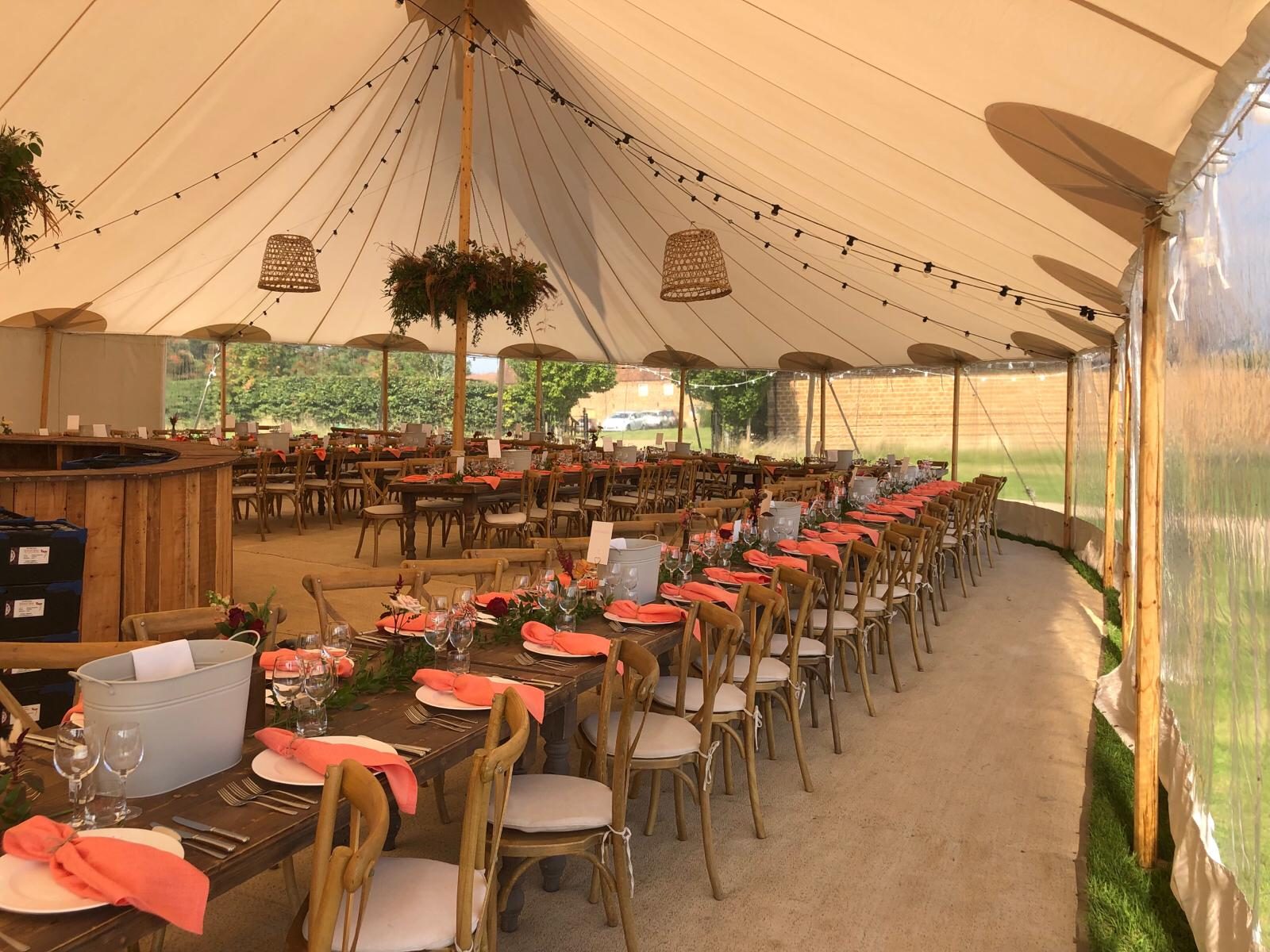 A marquee set up with a bar and dining tables for a professionally run event.