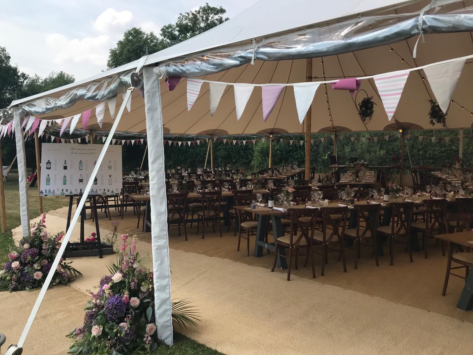 A marquee dressed with bunting and fresh flowers for a garden celebration.