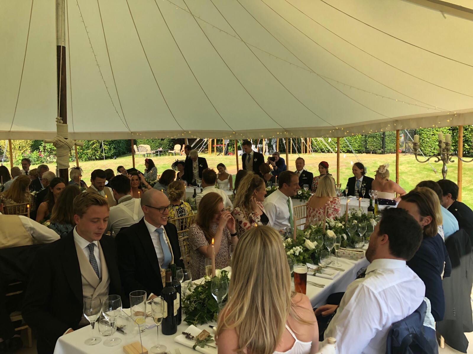 Guests enjoying a candlelit wedding breakfast in a marquee.