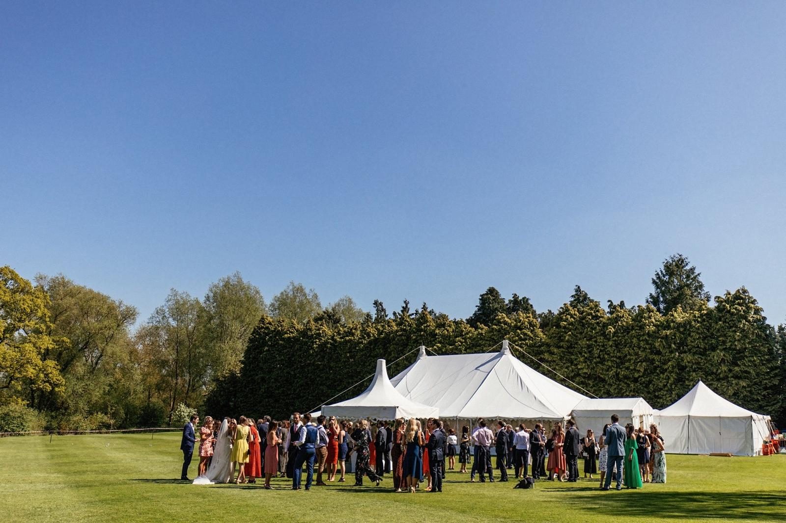 Wedding guests gathered on the lawn outside a marquee reception.