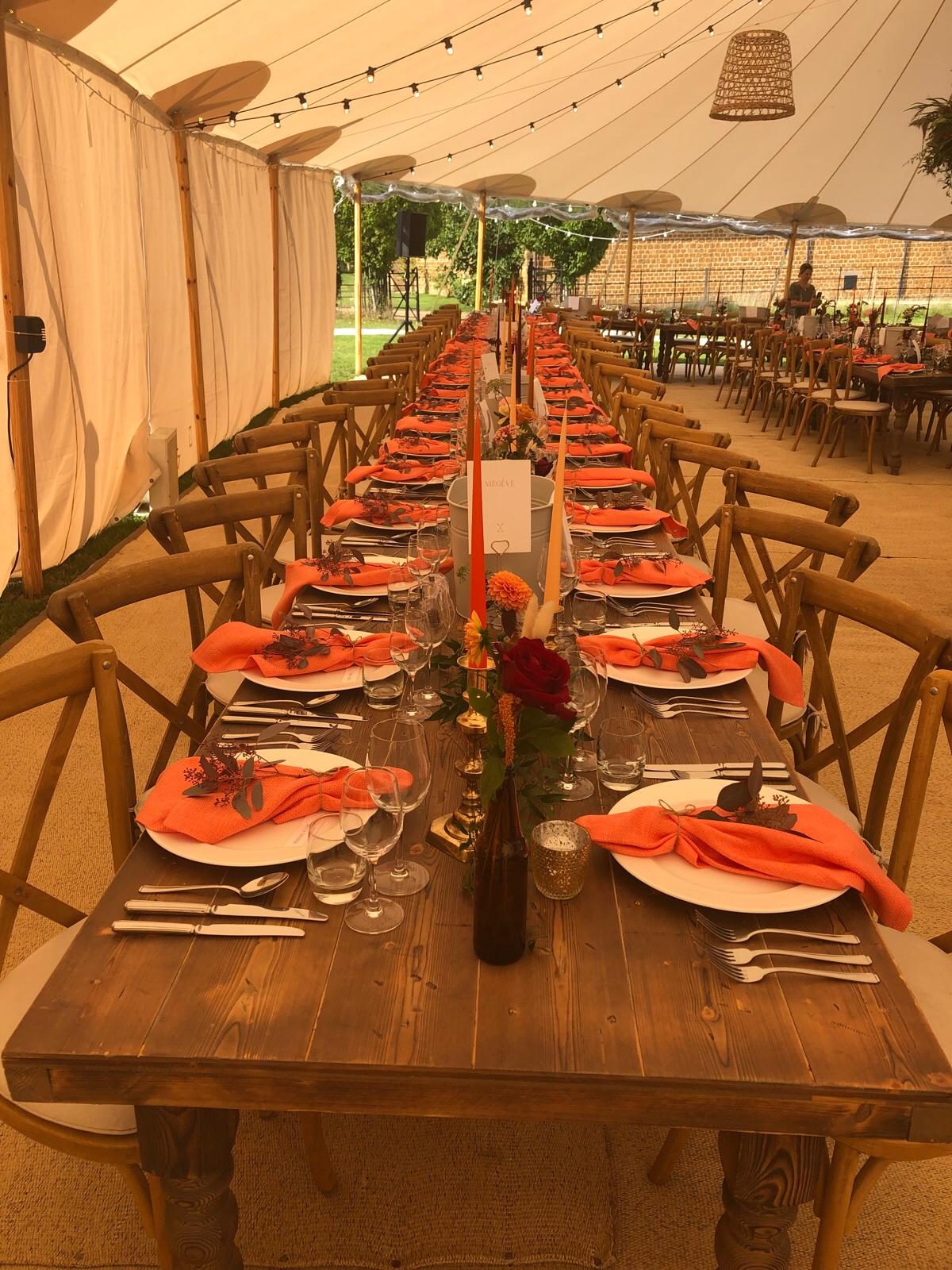 A marquee laid for a daytime event with long tables and place settings.