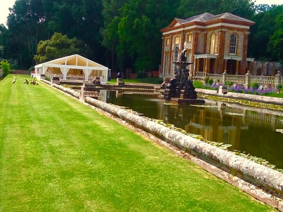 An orangery and fountain garden with a marquee set up on the lawn.