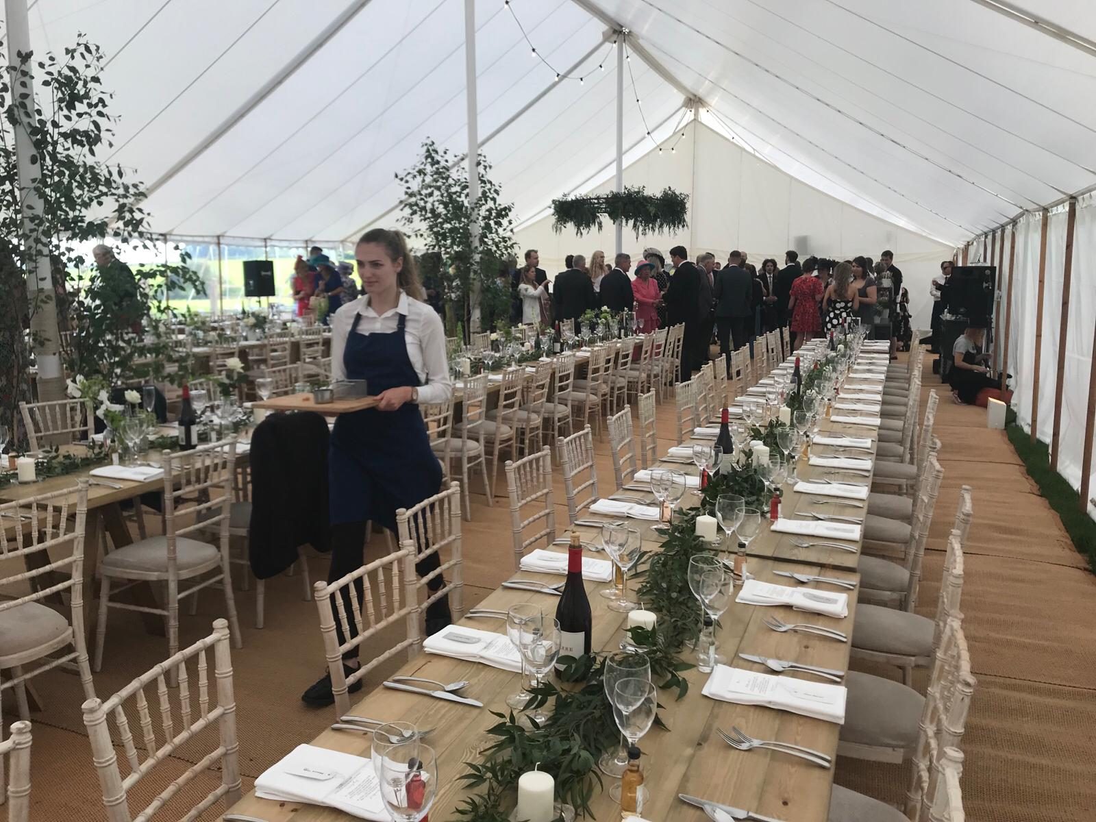 A member of staff serving guests at a marquee event.