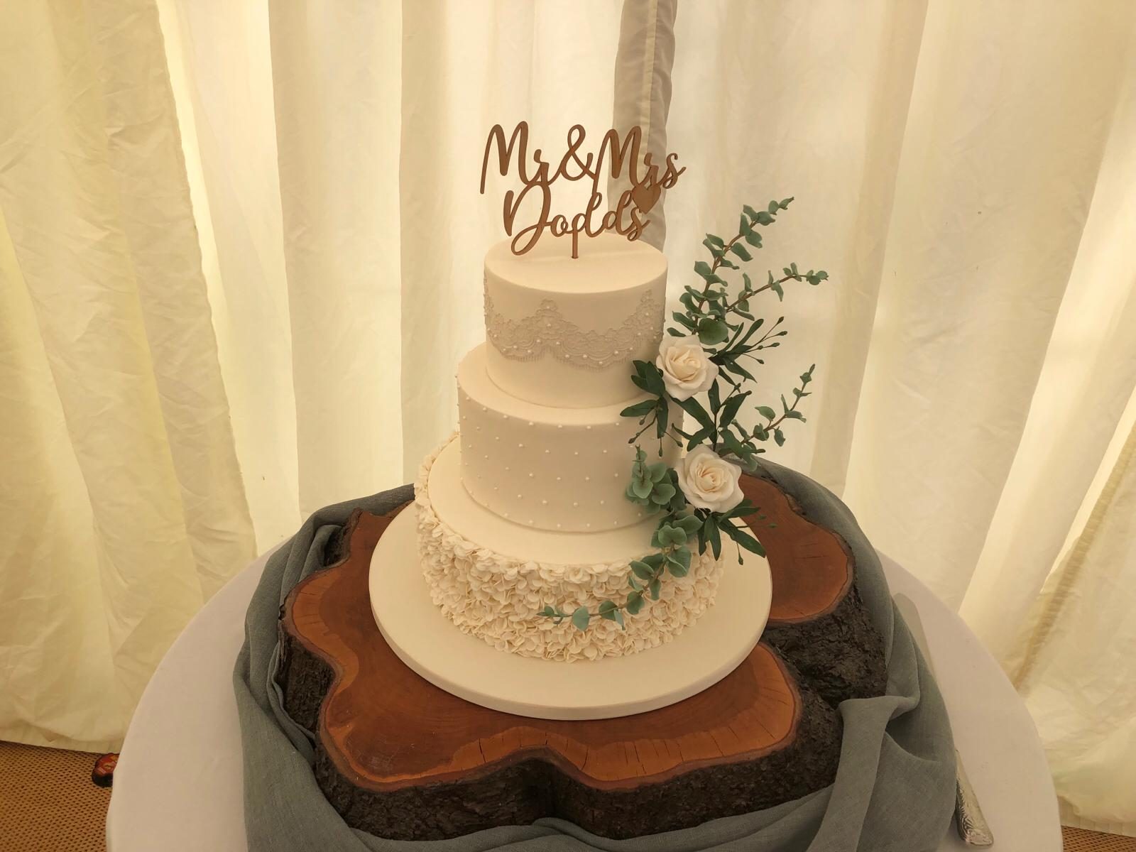 A three-tier wedding cake finished with sugar flowers and eucalyptus.